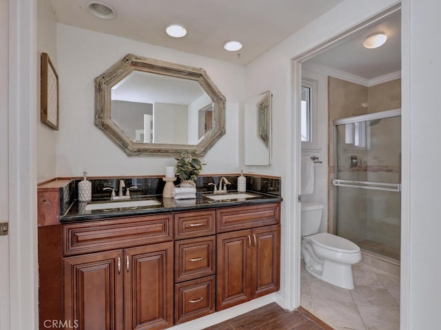 full bathroom featuring double vanity, toilet, a stall shower, and a sink
