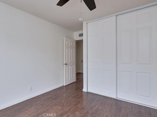 unfurnished bedroom featuring wood finished floors, a closet, ceiling fan, baseboards, and visible vents