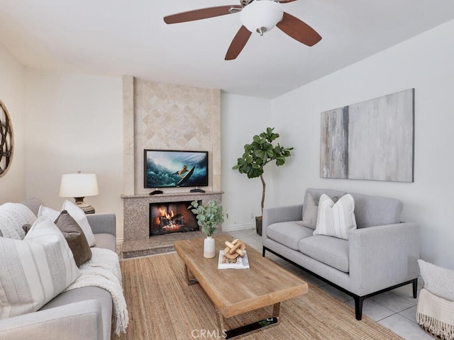 living area with a ceiling fan, baseboards, and a fireplace