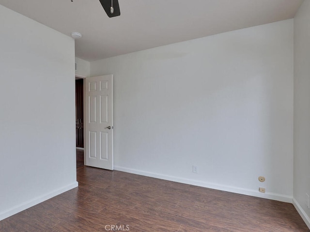 empty room featuring dark wood-style flooring, ceiling fan, and baseboards