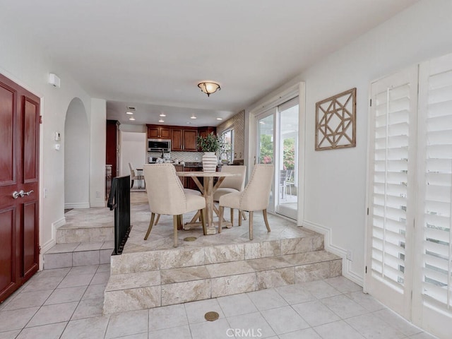 dining area with baseboards, recessed lighting, arched walkways, and light tile patterned flooring