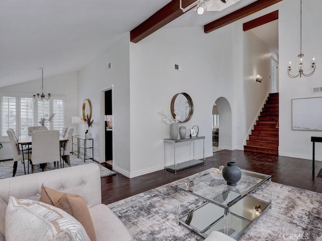 living area featuring arched walkways, wood finished floors, a chandelier, beamed ceiling, and stairway
