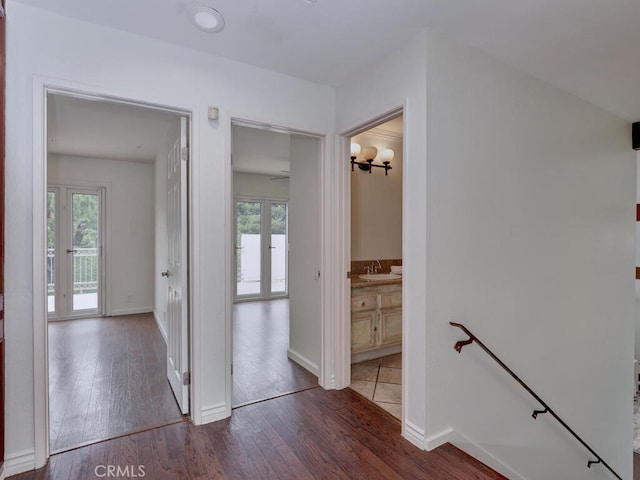 hall with an upstairs landing, a sink, hardwood / wood-style flooring, and plenty of natural light