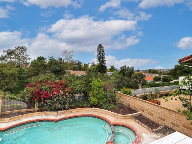 view of swimming pool featuring a fenced backyard and a pool with connected hot tub