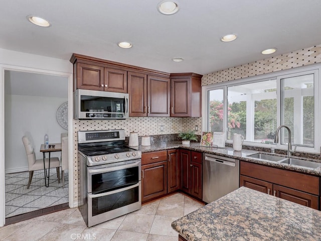 kitchen with dark stone countertops, recessed lighting, appliances with stainless steel finishes, and a sink