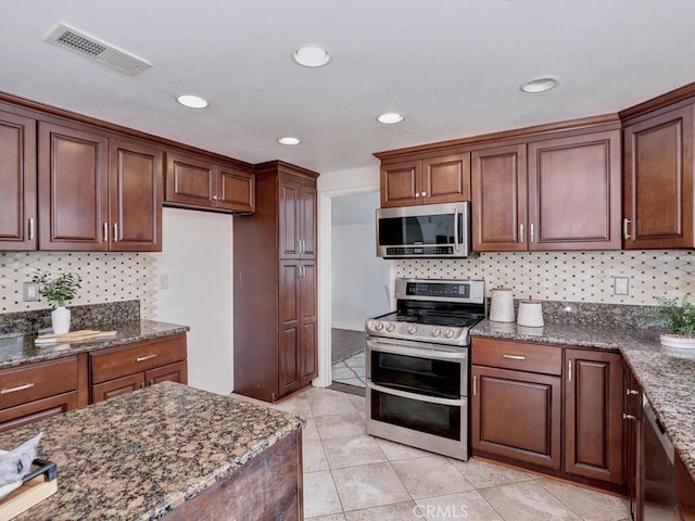 kitchen with visible vents, stainless steel appliances, decorative backsplash, and dark stone counters
