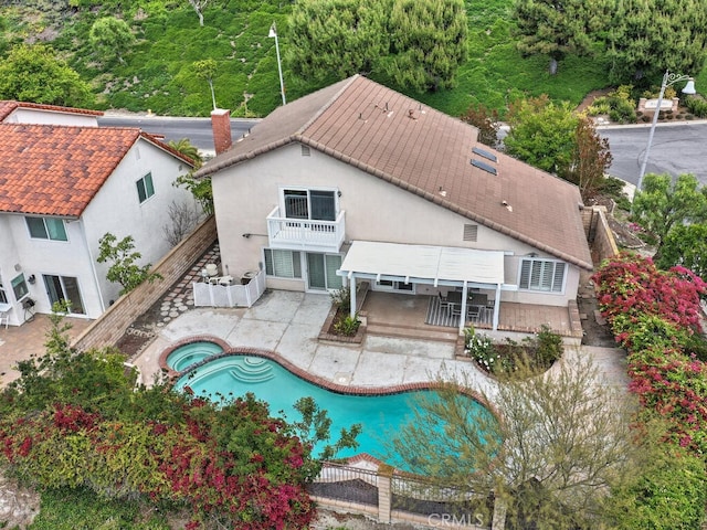 exterior space with a patio, a fenced backyard, an in ground hot tub, and a balcony