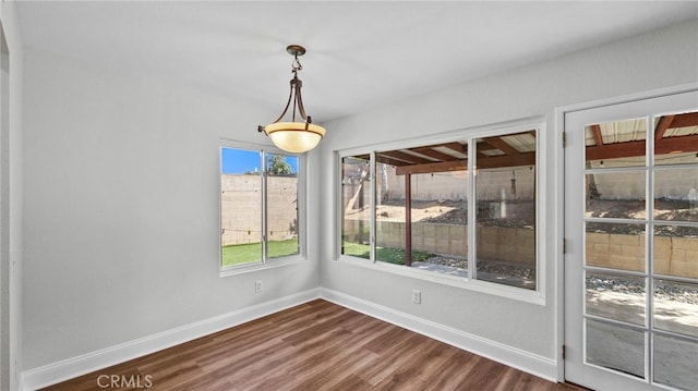 unfurnished dining area with baseboards and dark wood-style flooring