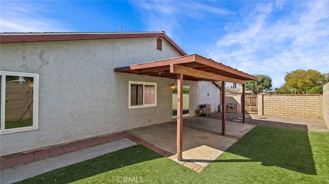 rear view of property with fence, stucco siding, a lawn, and a patio area
