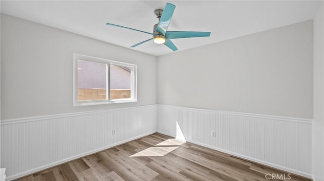 spare room with ceiling fan, wainscoting, and wood finished floors