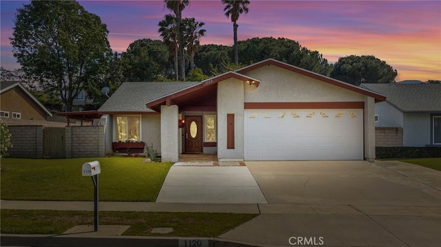 view of front of property with stucco siding, an attached garage, driveway, and a front lawn