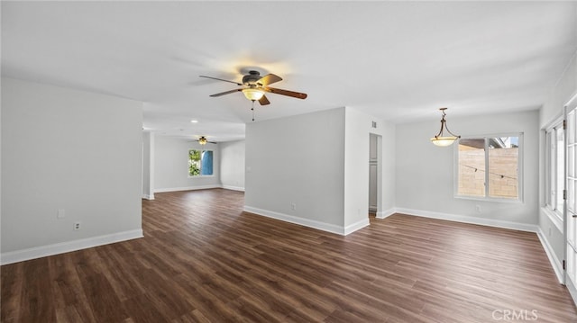 empty room with baseboards, a ceiling fan, dark wood-style flooring, and visible vents