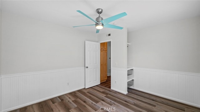 unfurnished bedroom with visible vents, ceiling fan, wood finished floors, and a wainscoted wall