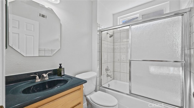 full bathroom featuring toilet, visible vents, bath / shower combo with glass door, and vanity