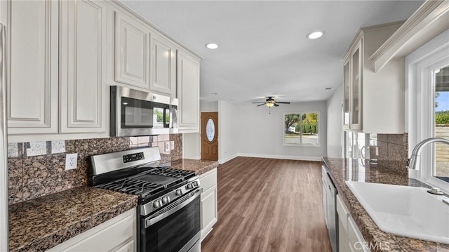 kitchen featuring decorative backsplash, baseboards, white cabinets, a sink, and appliances with stainless steel finishes