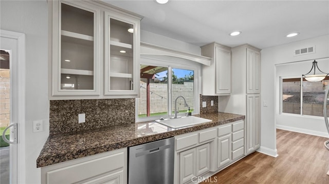 bar with visible vents, tasteful backsplash, stainless steel dishwasher, a sink, and light wood-style floors