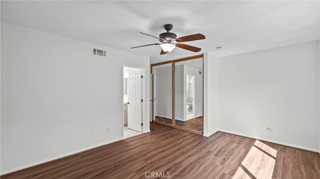 empty room with a ceiling fan, baseboards, visible vents, and wood finished floors