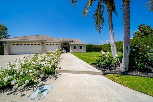 ranch-style home featuring concrete driveway, an attached garage, a front yard, and stucco siding