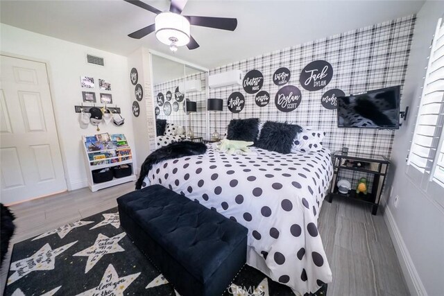 bedroom featuring baseboards, a ceiling fan, wood finished floors, and visible vents