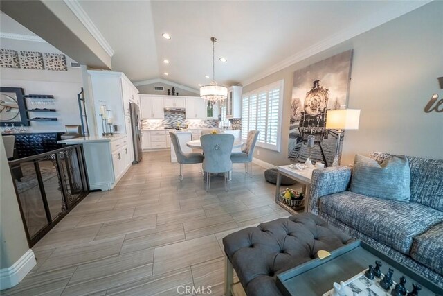 living area with an inviting chandelier, recessed lighting, baseboards, lofted ceiling, and ornamental molding