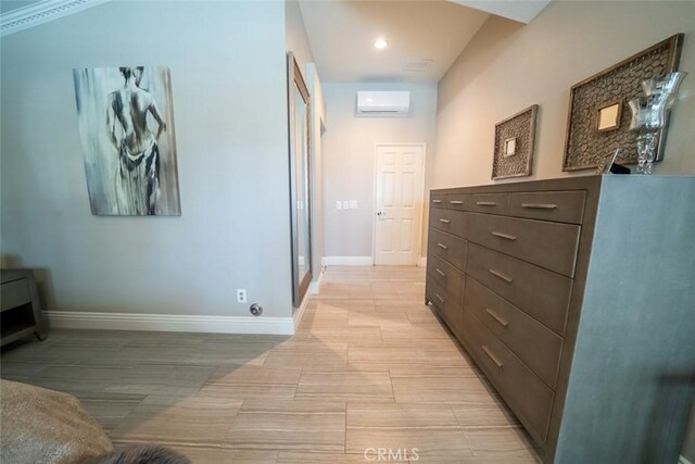 hall featuring baseboards, light wood-style flooring, and a wall mounted air conditioner