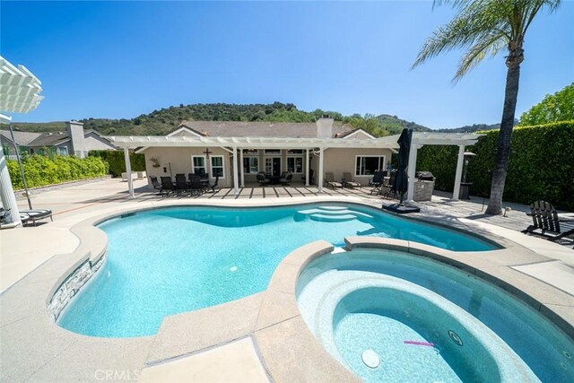 view of pool with a pergola, a pool with connected hot tub, and a patio