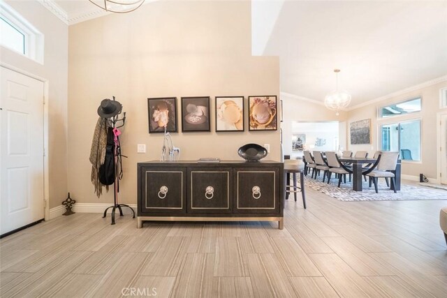 foyer with crown molding, baseboards, light wood finished floors, and a chandelier