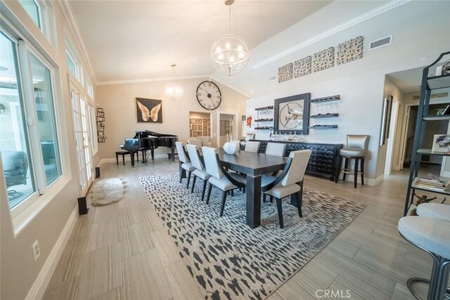dining space with crown molding, an inviting chandelier, baseboards, lofted ceiling, and visible vents