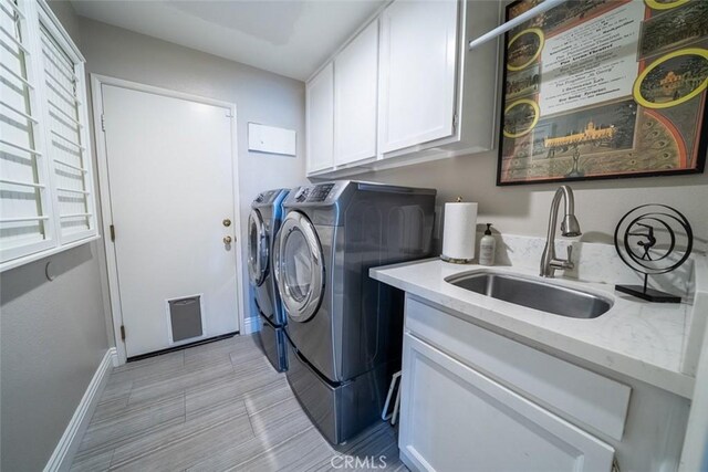 laundry room featuring visible vents, cabinet space, a sink, baseboards, and washer and dryer