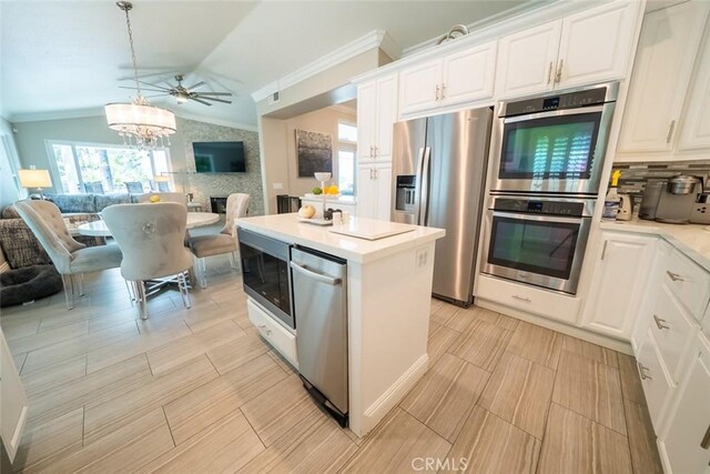 kitchen featuring crown molding, open floor plan, vaulted ceiling, and stainless steel appliances