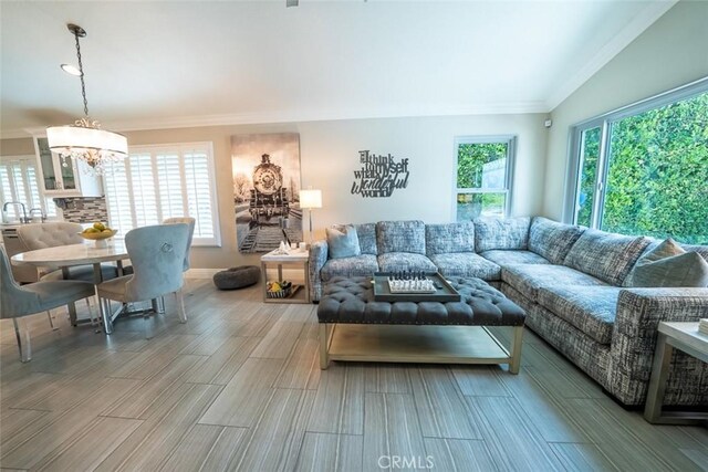living area featuring an inviting chandelier, crown molding, and wood finished floors