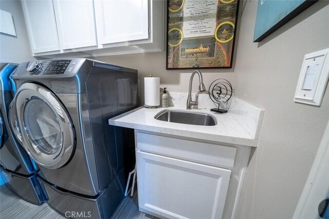 laundry room with a sink, washing machine and dryer, and cabinet space
