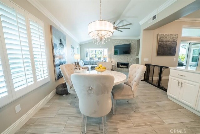 dining space with baseboards, ornamental molding, vaulted ceiling, and a large fireplace