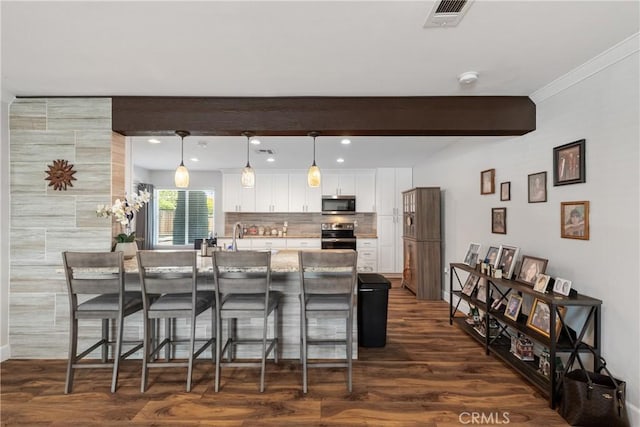 kitchen with stainless steel appliances, a kitchen breakfast bar, visible vents, white cabinetry, and dark wood finished floors