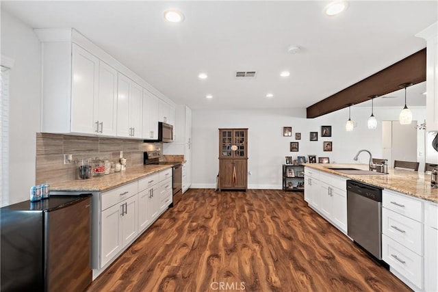 kitchen with a sink, stainless steel appliances, visible vents, a peninsula, and dark wood finished floors