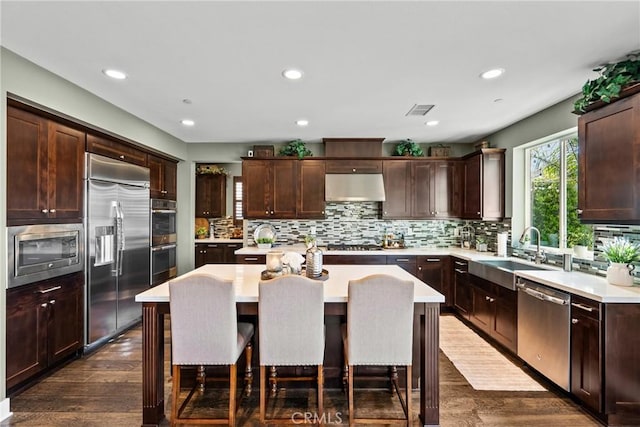 21609 Lucas Ct, Saugus, CA 91390 - kitchen featuring a sink, built in appliances, light countertops, under cabinet range hood, and a kitchen island