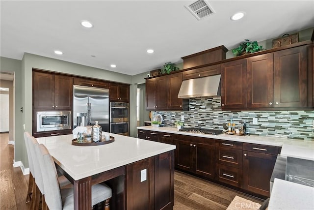 21609 Lucas Ct, Saugus, CA 91390 - kitchen with visible vents, built in appliances, range hood, light countertops, and backsplash
