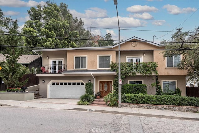 view of front of home with a garage, stucco siding, french doors, and a balcony