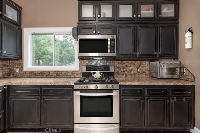 kitchen with decorative backsplash, glass insert cabinets, appliances with stainless steel finishes, light countertops, and a toaster