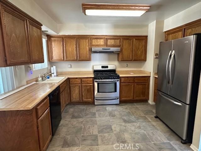 kitchen featuring brown cabinetry, a sink, stainless steel appliances, and under cabinet range hood