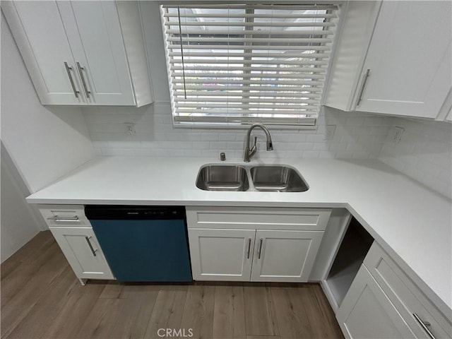 kitchen with white cabinetry, tasteful backsplash, a sink, light countertops, and dishwasher