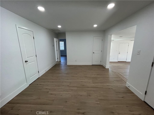 corridor with wood finished floors, recessed lighting, visible vents, and baseboards