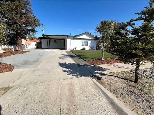 ranch-style house featuring stucco siding, fence, a carport, driveway, and a front yard