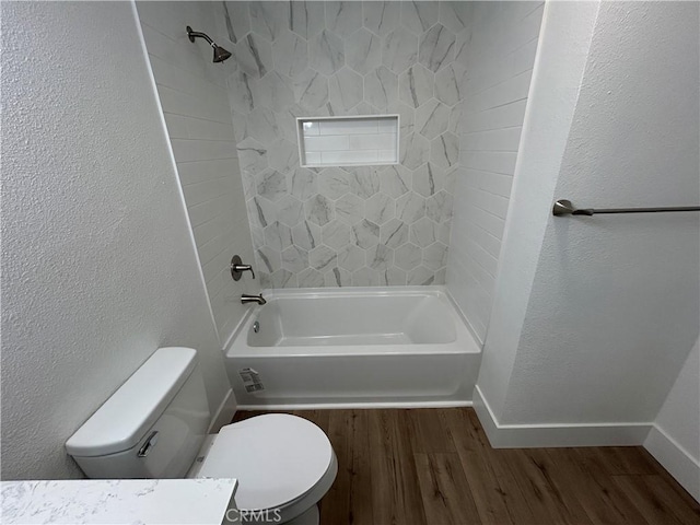 full bathroom featuring a textured wall, baseboards, toilet, shower / bathing tub combination, and wood finished floors