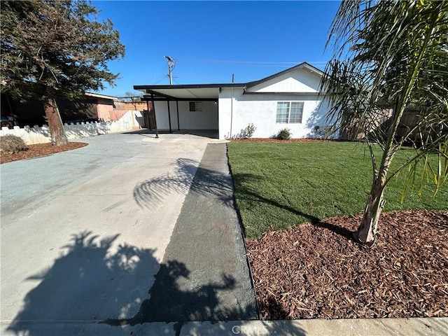 ranch-style home featuring stucco siding, fence, a carport, driveway, and a front lawn