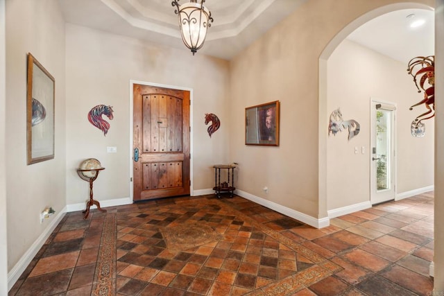 25444 Rancho Barona Rd, Ramona, CA 92065 - foyer entrance with arched walkways, baseboards, stone tile floors, inlaid floor details, and a raised ceiling