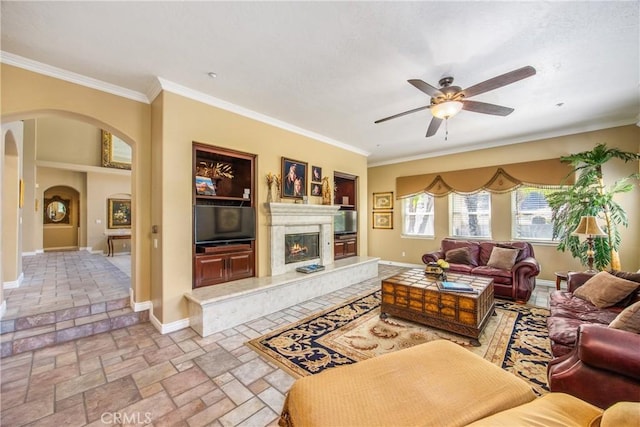 652 Fairway Dr, Redlands, CA 92373 - living room featuring a ceiling fan, ornamental molding, arched walkways, baseboards, and stone tile floors