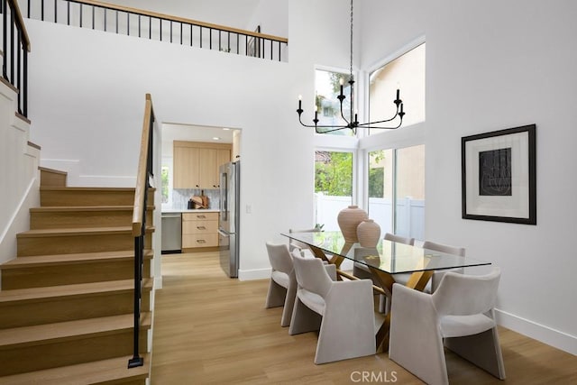 24411 Kings Vw, Laguna Niguel, CA 92677 - dining room with an inviting chandelier, a towering ceiling, baseboards, stairway, and light wood-style flooring
