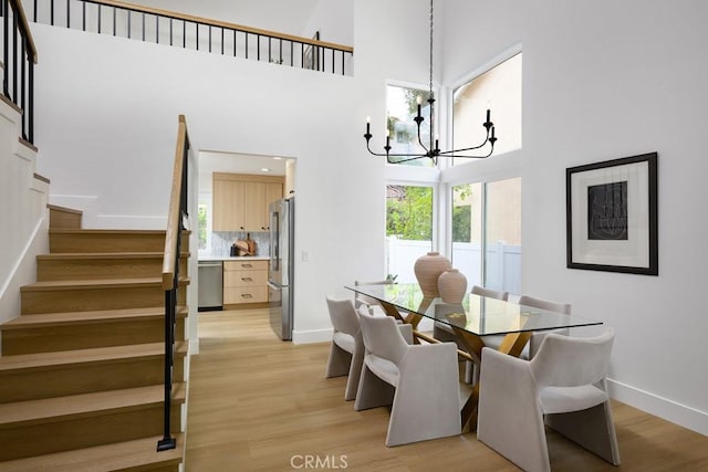 24411 Kings Vw, Laguna Niguel, CA 92677 - dining room with a chandelier, stairway, light wood-style floors, and a high ceiling