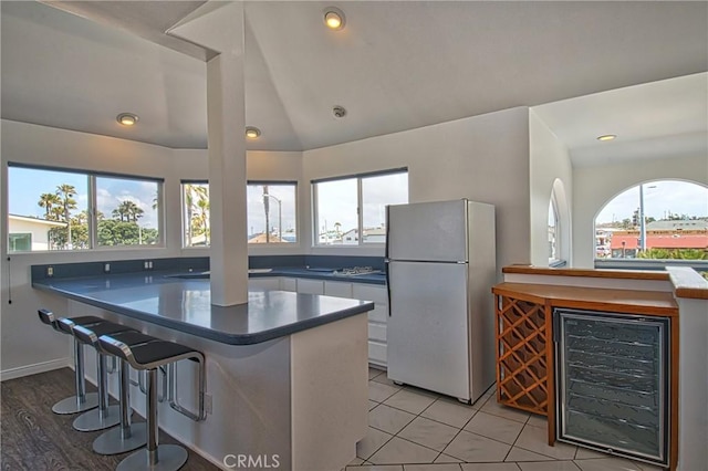6711 Seashore Dr, Newport Beach, CA 92663 - kitchen with a kitchen breakfast bar, white cabinets, freestanding refrigerator, wine cooler, and a peninsula